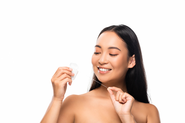 sonriente asiático desnudo mujer mirando dental hilo aislado en blanco
 - Foto, imagen