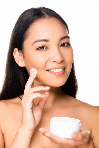nahá krásná asijská žena s kosmetickým krémem na prstech izolovaných na bílém - Fotografie, Obrázek