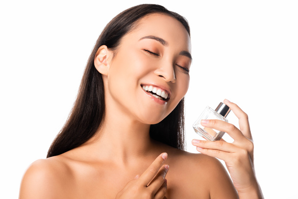 laughing naked beautiful asian woman holding perfume isolated on white - Фото, зображення