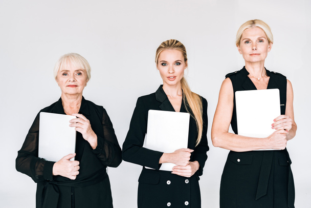 модные блондинки в трех поколениях в черных костюмах с чистыми досками, изолированными на сером
 - Фото, изображение