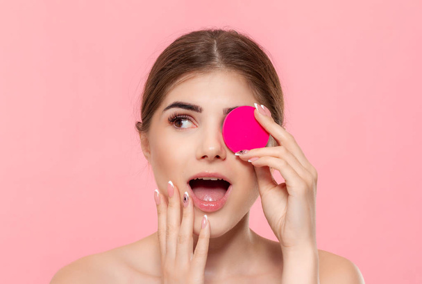 Hermoso modelo applyes producto cosmético para la piel con esponja de algodón rosa
. - Foto, imagen