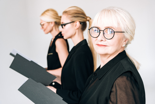 femmes d'affaires de trois générations dans des lunettes avec des dossiers isolés sur gris
 - Photo, image