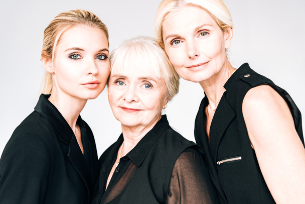 Portret van elegante drie-generatie blonde vrouwen in totaal zwarte outfits geïsoleerd op grijs - Foto, afbeelding