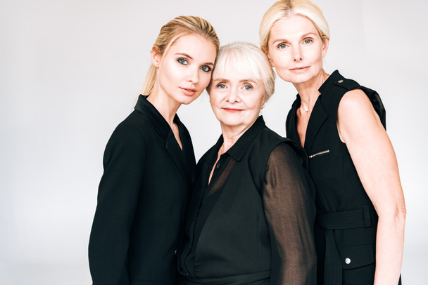 elegant three-generation blonde women in total black outfits isolated on grey - Foto, imagen