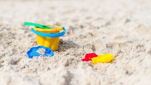 Игрушки на пляже - пластиковые желтые ведра, грабли, лопатки, пресс-формы
  - Фото, изображение