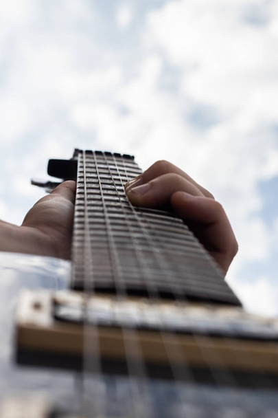 Mužská ruka hrající na elektrickou kytaru a ohýbání struny - Fotografie, Obrázek