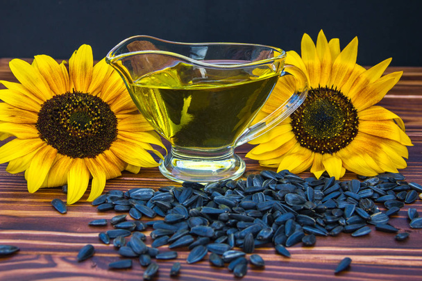 Holzhintergrund mit Sonnenblumenöl, Samen und einer Sonnenblume - Foto, Bild