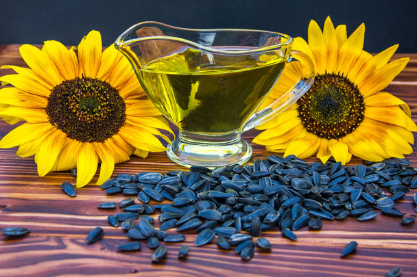 Holzhintergrund mit Sonnenblumenöl, Samen und einer Sonnenblume - Foto, Bild