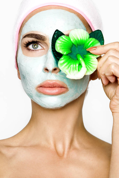 Young smiling woman with a clay mask. Photo of attractive young woman covering her eyes with cucumbers on a white background. Grooming himself - Image - Photo, Image