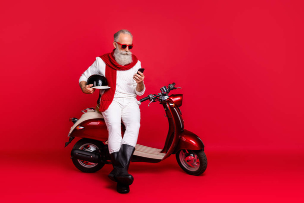 Aged macho man sit on retro moped chatting telephone wear jumper and trousers isolated red background - Foto, Bild