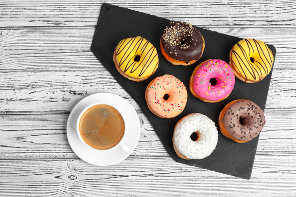 Several fresh donuts in a black ceramic plate on a wooden table with copy space - Foto, afbeelding