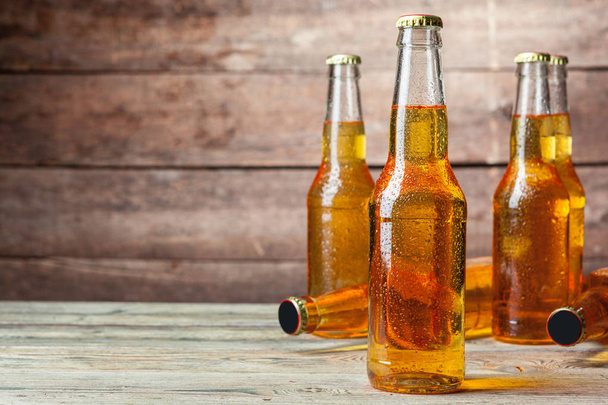 Fresh beer in glass bottles on wooden background - 写真・画像