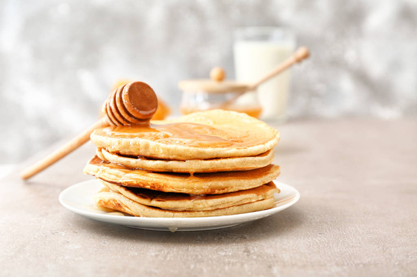 Smakelijke pannenkoeken met honing op een grijze tafel - Foto, afbeelding