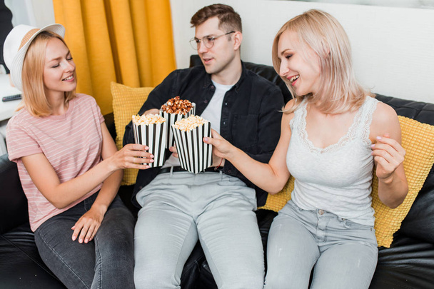 Cheerful group of friends eating popcorn at home - Fotoğraf, Görsel