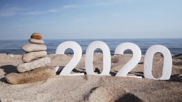2020 yılı, deniz kıyısındaki taşlar ve kabuklar arasında kum üzerinde sayılar. Yeni Yıl 2020 kavramı geliyor - bir kum plajda rakamlar. Yeni yıl tatili. Close. - Video, Çekim