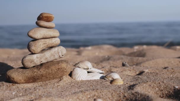 Torre de piedra en la playa al atardecer. Primer plano de pila de guijarros balanceados en la playa. Pirámide de piedras para la meditación en las vacaciones de verano
.  - Imágenes, Vídeo