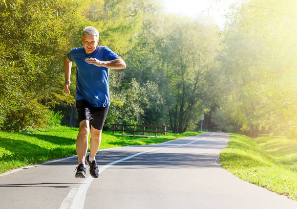 Homem ativo de meia-idade correndo no parque público
 - Foto, Imagem