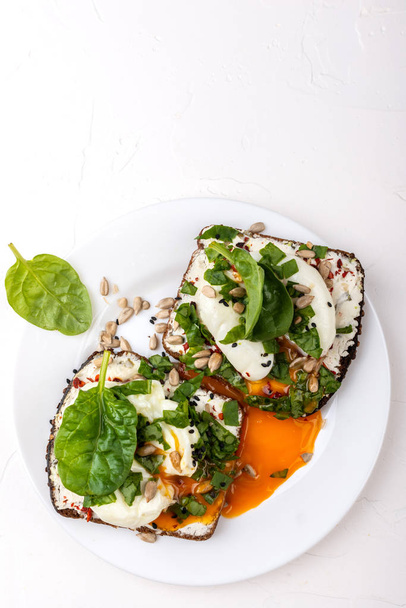 Sandwiches with poached eggs, cheese, spinach leaves, sesame seeds and seeds. Healthy breakfast or snack on the white background. Copy space - Photo, Image