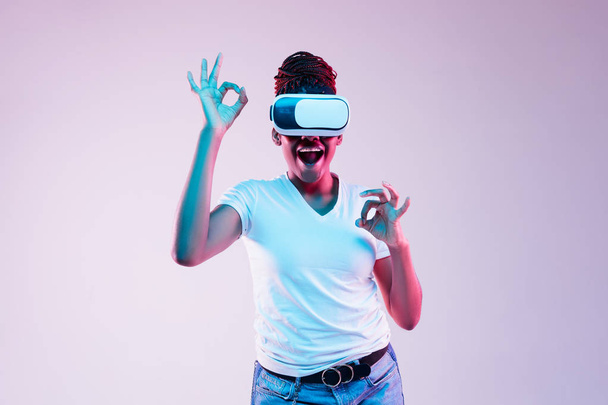Young african-american womans using VR-glasses in neon light - Фото, зображення