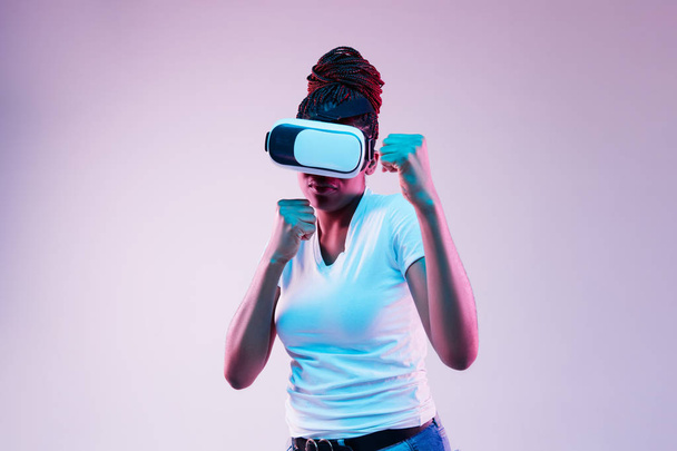 Young african-american womans using VR-glasses in neon light - Foto, Bild