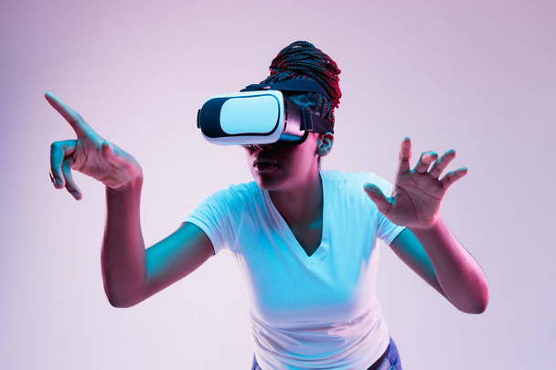Mujeres afroamericanas jóvenes usando gafas VR en luz de neón
 - Foto, Imagen