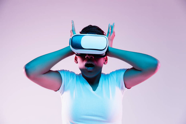 Young african-american womans using VR-glasses in neon light - Foto, immagini