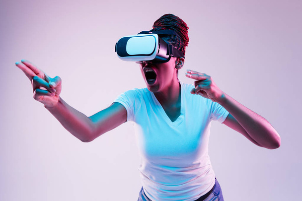 Young african-american womans using VR-glasses in neon light - Photo, image