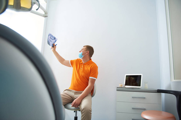 Male dentist is analyzing results of orthopantomogram - Фото, зображення