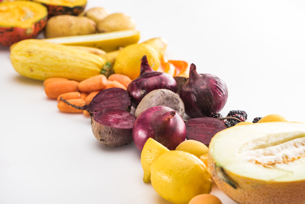 rode uien, bieten, wortelen, citroenen, courgette en meloen helft op witte achtergrond - Foto, afbeelding