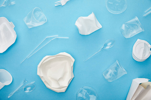 vista superior de copos de plástico descartáveis, garfos, colheres e recipientes em fundo azul
 - Foto, Imagem