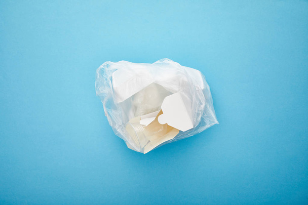 vista superior do saco de plástico com recipientes de papelão descartáveis em fundo azul
 - Foto, Imagem