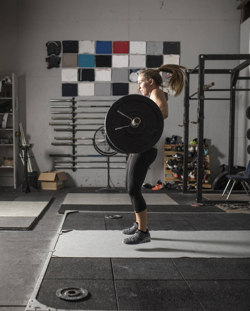 Action shot of female power lifter doing clean and jerk with hea - Foto, Imagen