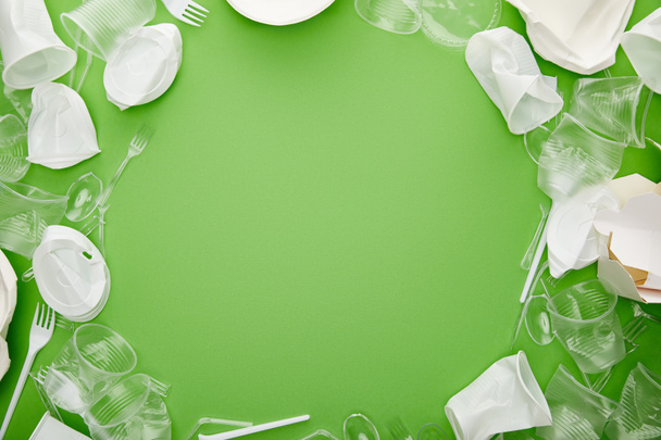 vista superior de copos de plástico amassado, garfos, placas e recipiente de papelão em fundo verde com espaço de cópia
 - Foto, Imagem