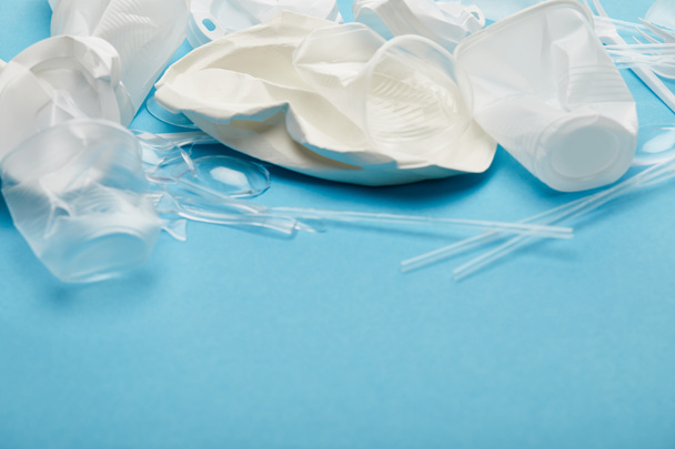 zmačkané bílé a průhledné Plastové šálky a talíře na modrém pozadí - Fotografie, Obrázek