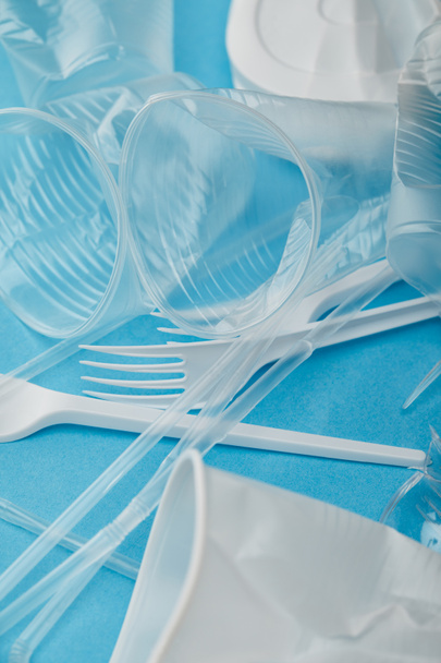 pile of crumpled plastic cups and forks on blue background - 写真・画像