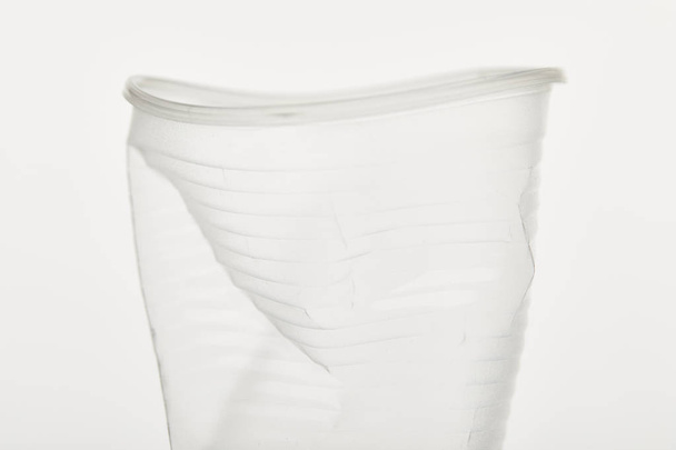 close up view of crumpled transparent plastic cup on white background - Photo, Image