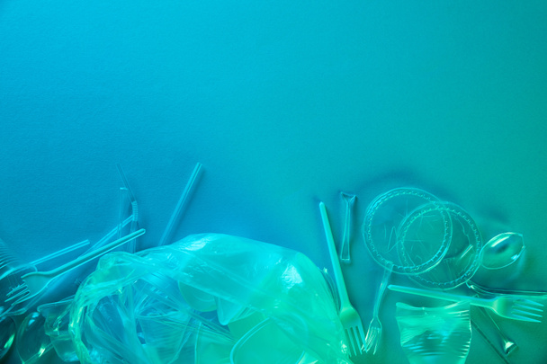 vista superior de sacos de plástico amassados, copos e lixo de papelão com espaço de cópia em luz azul
 - Foto, Imagem