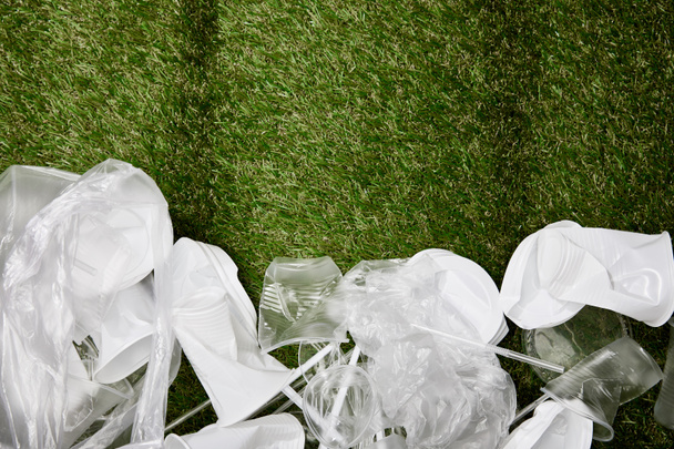 vista superior de plástico amassado e lixo de papelão na grama com espaço de cópia
 - Foto, Imagem
