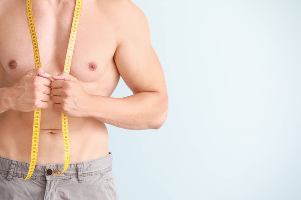 Handsome muscular man with measuring tape on color background. Weight loss concept - Photo, Image