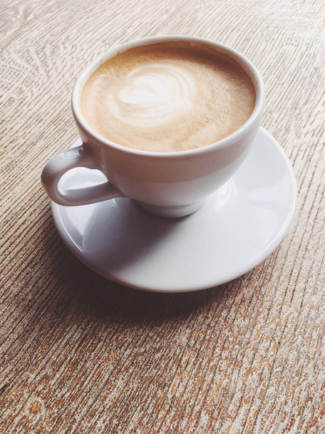 Чашка горячего капучино в кафетерии, кофе на деревянном столе и...
 - Фото, изображение