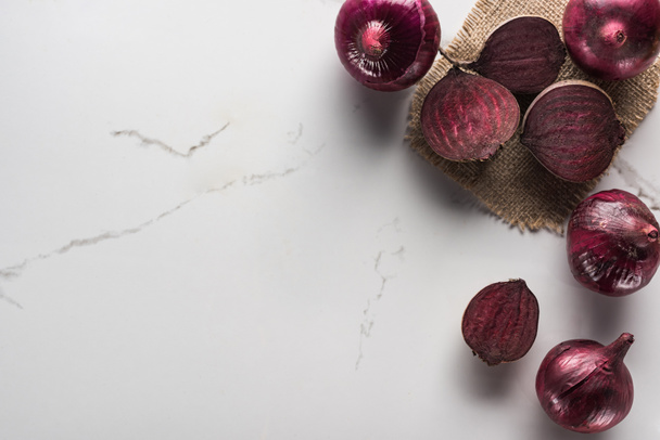 top view of red onions and beetroots on marble surface with hessian - Photo, Image