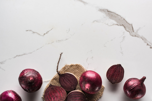 top view of beetroots and red onions on marble surface with hessian - Photo, Image
