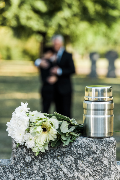 selective focus of flowers and mortuary urn on tombstone - Φωτογραφία, εικόνα