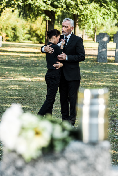 selective focus of senior man hugging upset woman in cemetery  - Photo, Image