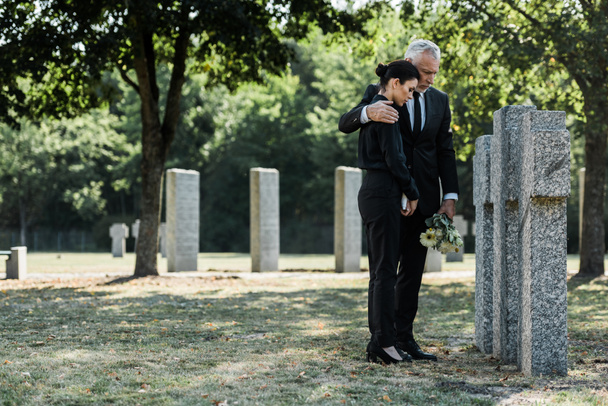 hombre molesto abrazando a mujer frustrada en el cementerio
  - Foto, Imagen