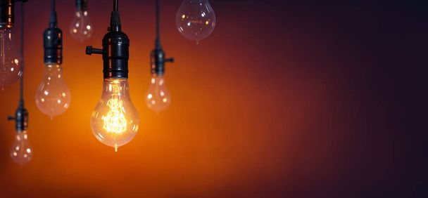 Leadership And Innovation Concept - Standing Out From The Crowd - Glowing Bulb On Among Bulbs Off - 写真・画像
