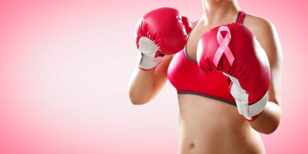 Strijd tegen borstkanker-Boxer vrouw met bokshandschoenen en roze lint - Foto, afbeelding