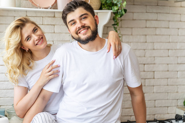 Happy young couple is standing in kitchen - Fotografie, Obrázek
