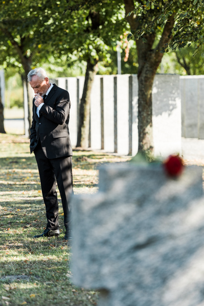 selective focus of upset man standing on graveyard  - Photo, image