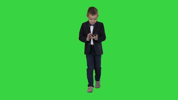 Mały chłopiec w kostiumie chodzenie i za pomocą smartfona na zielonym ekranie, Klucz chrominancji. - Materiał filmowy, wideo